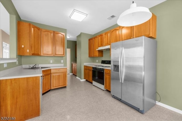 kitchen featuring stainless steel fridge, a sink, gas range, under cabinet range hood, and visible vents