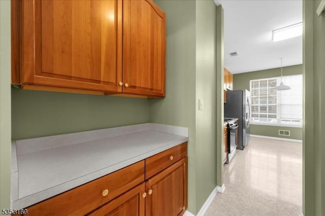 interior space featuring light countertops, baseboards, visible vents, and range with electric stovetop