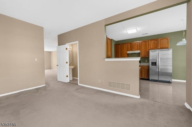 unfurnished living room with visible vents, baseboards, and light colored carpet