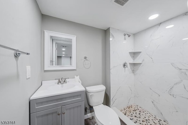 bathroom with visible vents, a marble finish shower, toilet, and vanity