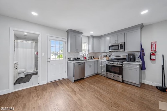kitchen with light countertops, stainless steel appliances, gray cabinetry, and a sink