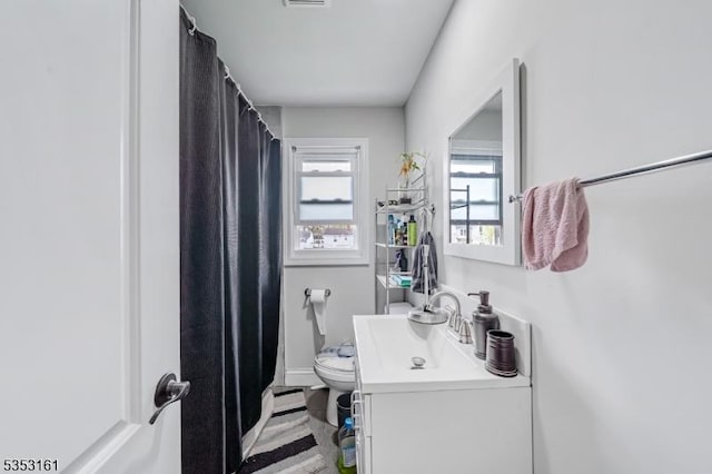 full bathroom with vanity, a shower with curtain, toilet, and visible vents