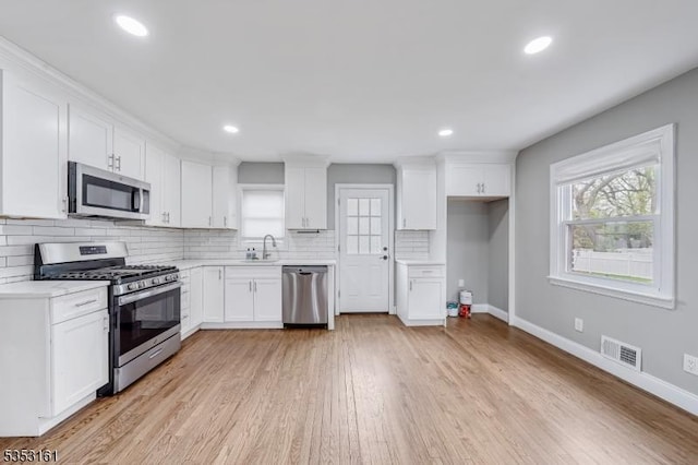 kitchen with a sink, white cabinets, stainless steel appliances, and visible vents