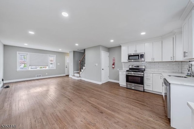 kitchen featuring a sink, light countertops, stainless steel appliances, baseboards, and tasteful backsplash