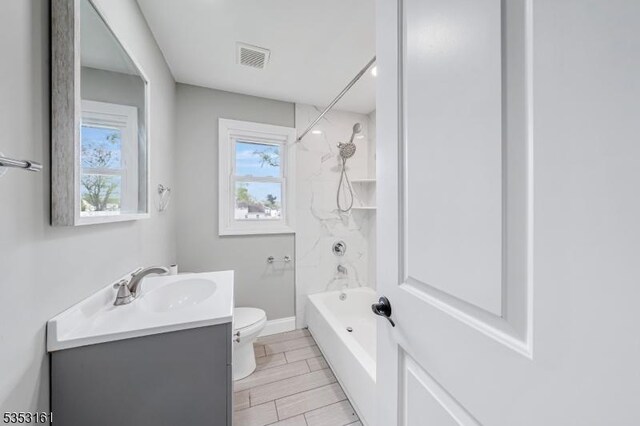 bathroom featuring vanity, visible vents, toilet, baseboards, and washtub / shower combination