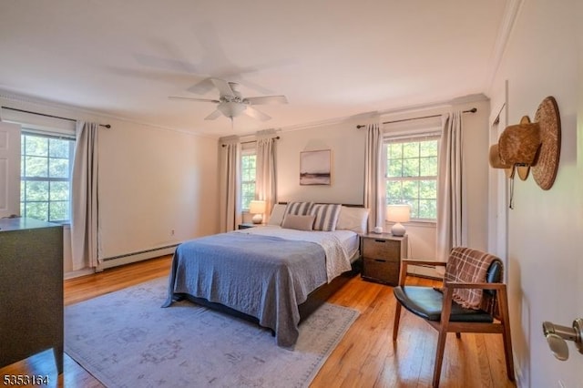 bedroom with crown molding, multiple windows, baseboard heating, and light wood finished floors