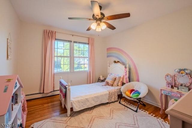 bedroom with ceiling fan, a baseboard heating unit, and wood finished floors