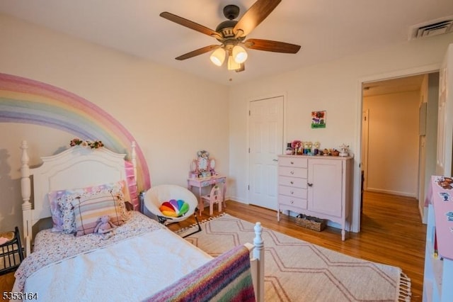 bedroom with a ceiling fan, baseboards, visible vents, and wood finished floors
