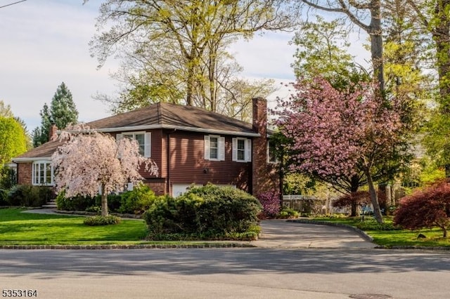 view of front of house with a front lawn, driveway, and a chimney