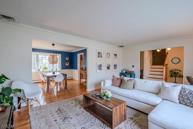 living area with light wood finished floors, stairs, a baseboard radiator, visible vents, and ornamental molding