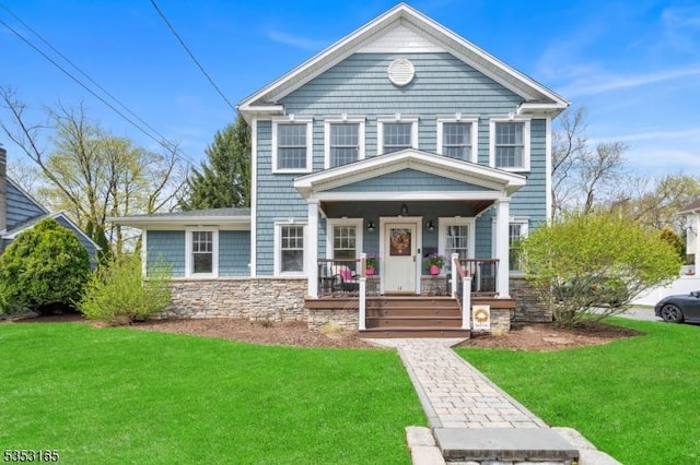 view of front of house featuring covered porch, a front lawn, and stone siding