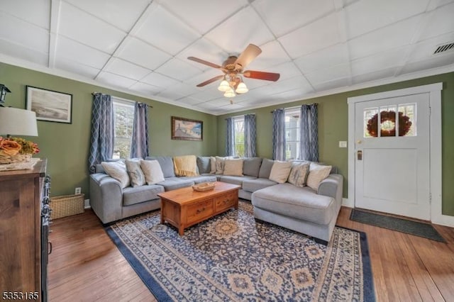 living area with wood-type flooring, crown molding, and a ceiling fan