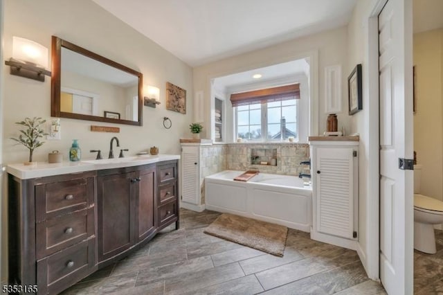 full bathroom featuring toilet, a bath, and vanity