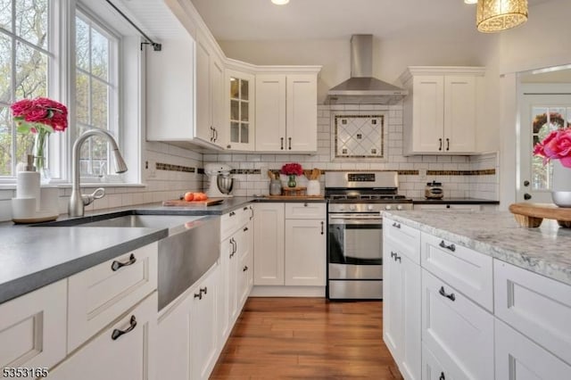 kitchen featuring stainless steel gas range, a sink, wall chimney range hood, and plenty of natural light