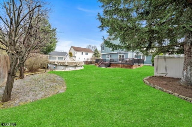 view of yard with a fenced in pool, a storage unit, a wooden deck, and an outbuilding