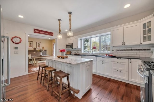 kitchen with a center island, white cabinetry, stainless steel appliances, and decorative backsplash