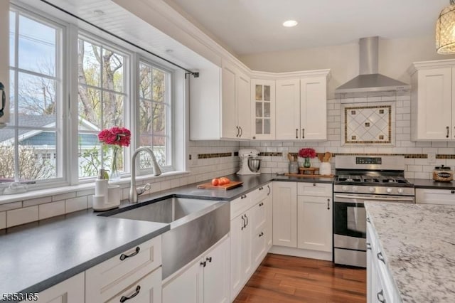 kitchen with wall chimney exhaust hood, a sink, gas range, and a healthy amount of sunlight