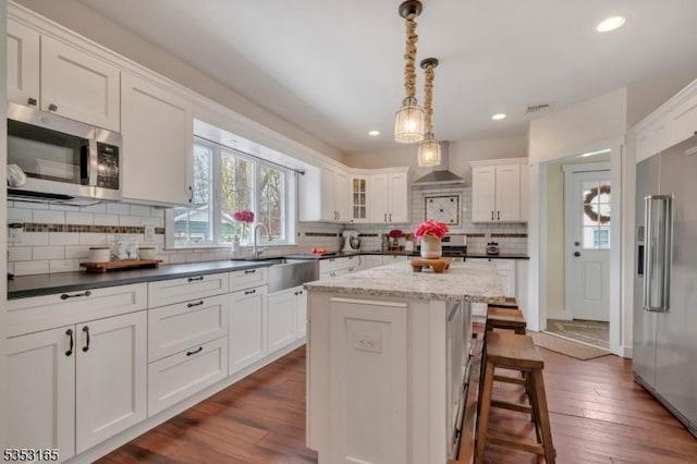 kitchen featuring stainless steel appliances, backsplash, a sink, white cabinetry, and visible vents