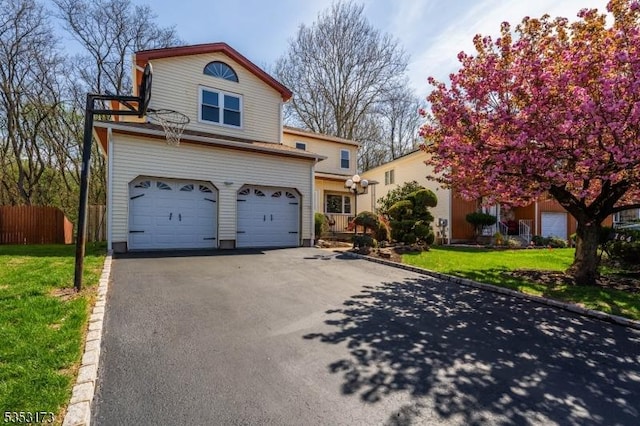 traditional-style house featuring an attached garage, fence, driveway, and a front yard