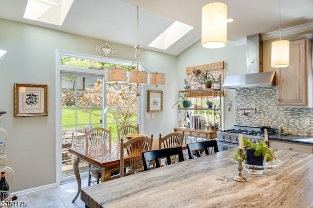 dining room featuring light tile patterned floors, a skylight, and baseboards