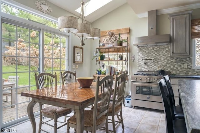 dining area with light tile patterned floors and vaulted ceiling with skylight