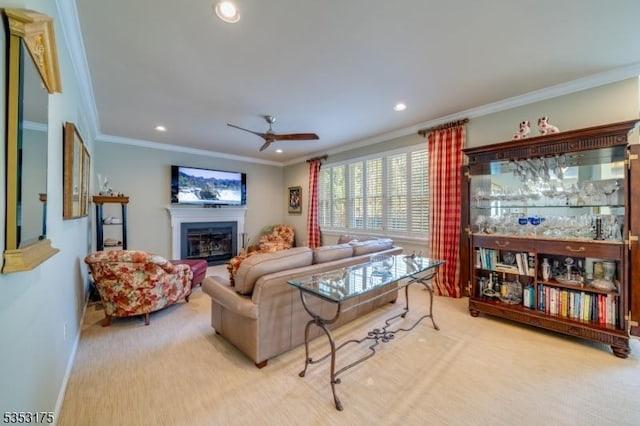 carpeted living room with a glass covered fireplace, ceiling fan, ornamental molding, and recessed lighting