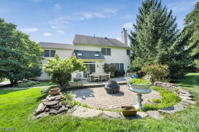 rear view of property featuring a patio, a chimney, and a yard