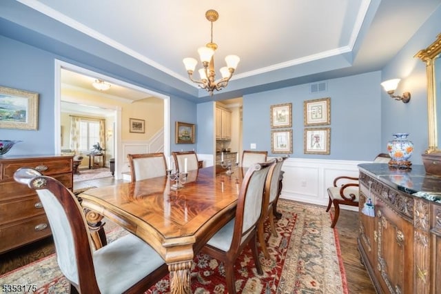dining space with visible vents, wainscoting, a decorative wall, and a notable chandelier
