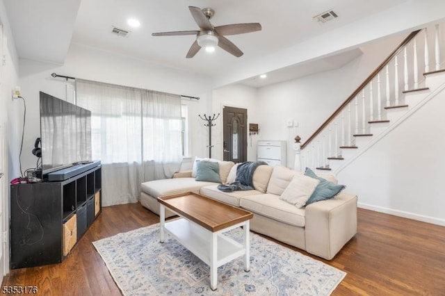 living room with ceiling fan, visible vents, wood finished floors, and stairway