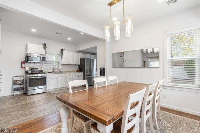 dining area with beam ceiling, recessed lighting, light wood-style flooring, and visible vents