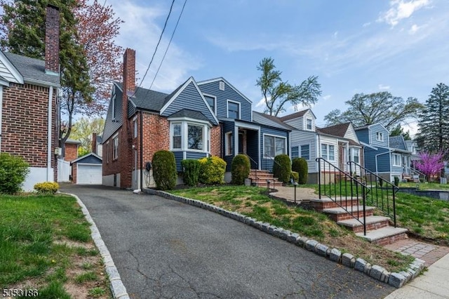view of front facade featuring brick siding, a chimney, an outdoor structure, and a garage