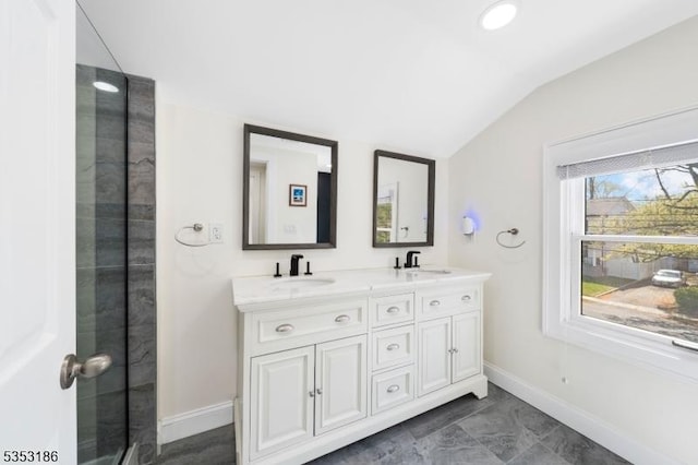 full bathroom with double vanity, baseboards, vaulted ceiling, and a sink