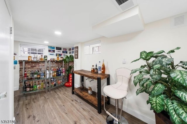 bar with baseboards, visible vents, a dry bar, and wood finished floors