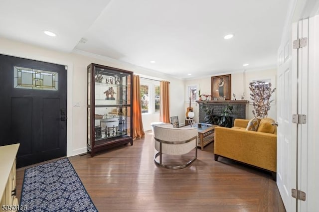 foyer entrance with crown molding, recessed lighting, wood finished floors, and a fireplace