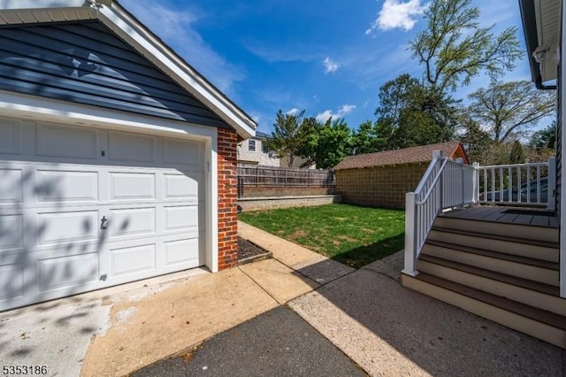 garage featuring concrete driveway and fence