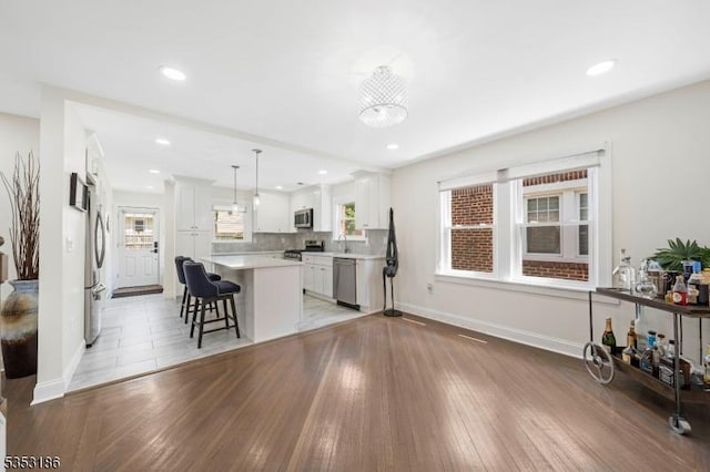 living room with recessed lighting, baseboards, and light wood-style flooring