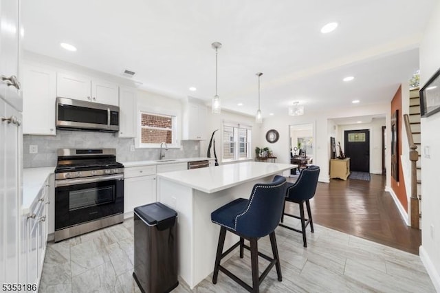 kitchen featuring a kitchen island, stainless steel appliances, recessed lighting, and a sink