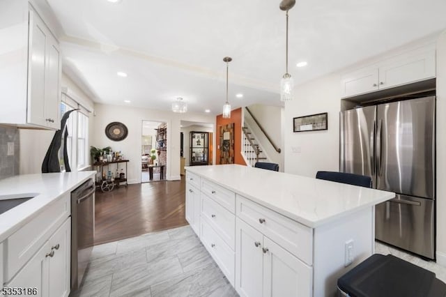 kitchen featuring appliances with stainless steel finishes, a center island, white cabinetry, and decorative light fixtures