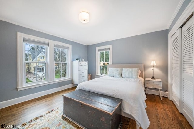 bedroom featuring crown molding, wood finished floors, baseboards, and a closet