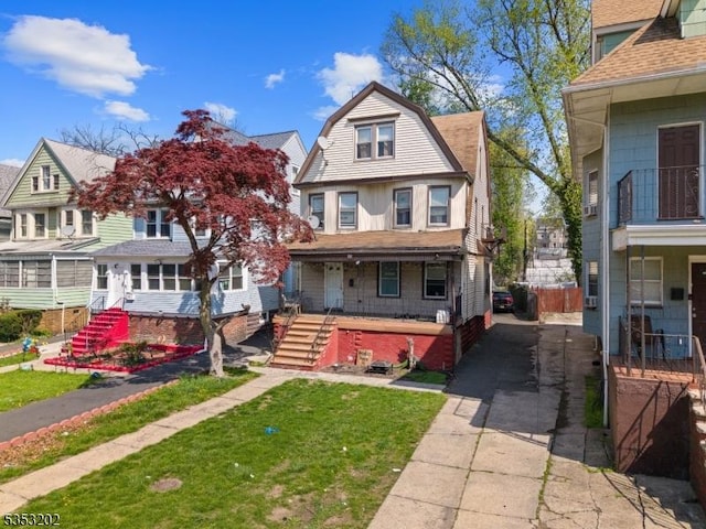 view of front of property featuring stairs, a porch, a gambrel roof, driveway, and a front lawn