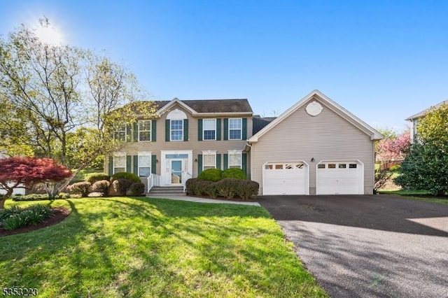 colonial home featuring a garage, a front yard, and aphalt driveway