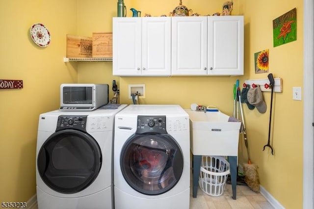 laundry area featuring a sink, baseboards, cabinet space, and washing machine and clothes dryer