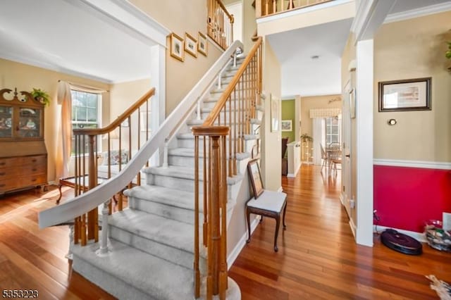 stairway featuring wood-type flooring, baseboards, and ornamental molding
