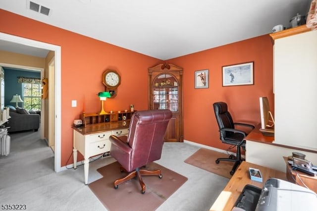 office space featuring baseboards, visible vents, and light carpet