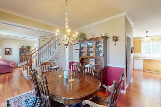 dining space featuring ornamental molding, light wood finished floors, a chandelier, and stairway