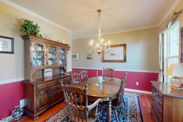 dining room featuring crown molding, baseboards, wood finished floors, and a notable chandelier