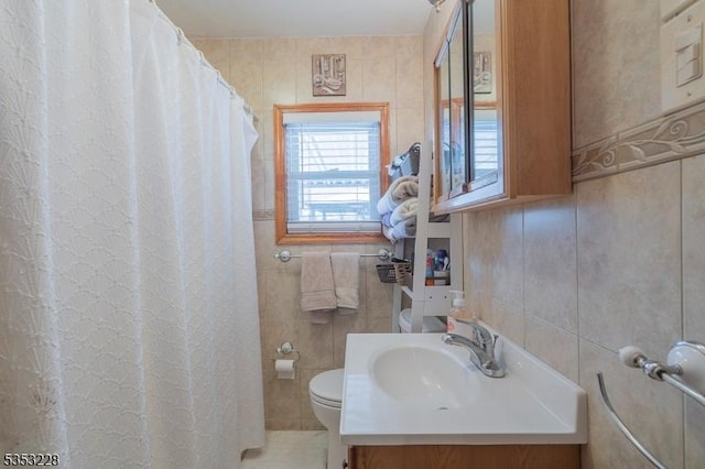 bathroom featuring toilet, tile walls, and vanity
