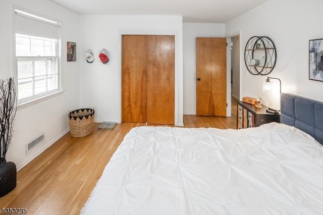bedroom with baseboards, visible vents, and wood finished floors