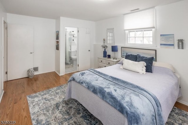 bedroom with wood finished floors, connected bathroom, and visible vents
