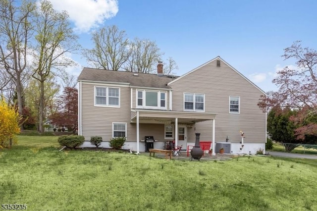 rear view of property with a lawn, a chimney, central AC, and a patio